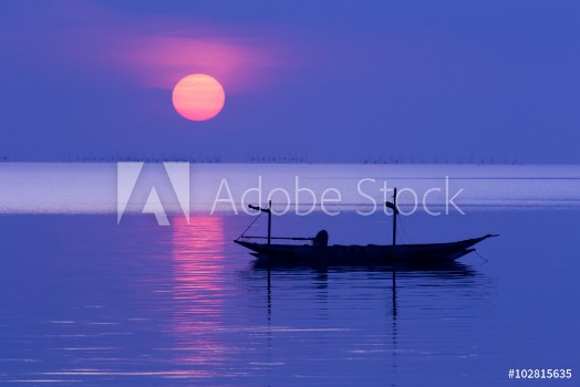 Bild på Peaceful Morning at sunrise with small boat silhouette in the beach